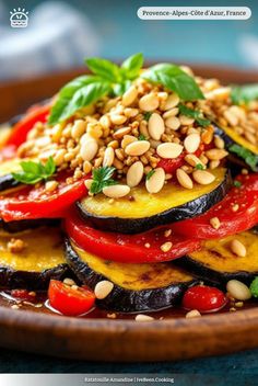 a wooden bowl filled with sliced eggplant, tomatoes and other veggies