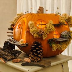 a carved pumpkin with moss and pine cones on the top, surrounded by other decorations