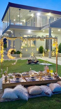 a table set up outside with food and decorations on the grass in front of a house