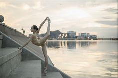 a woman in a leotard stretching on some steps by the water