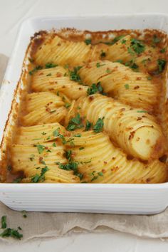 a casserole dish filled with potatoes and garnished with parsley