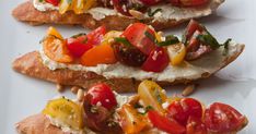 three pieces of bread with tomatoes and other vegetables on them sitting on a white plate