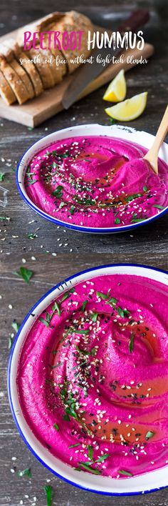 two plates filled with pink hummus on top of a wooden table