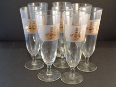 six wine glasses sitting next to each other on top of a black tablecloth covered surface