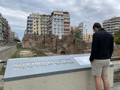 a man standing on top of a cement wall next to a sign that reads,