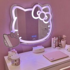 a hello kitty mirror sitting on top of a white desk next to a laptop computer