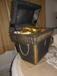 an open black box with gold foil in it on top of a white bedspread