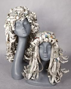 two mannequin heads are covered with silver leaves and beads, one is wearing a headdress