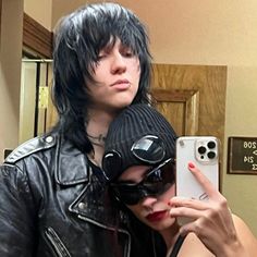 a woman taking a selfie with a man in a black leather jacket and hat