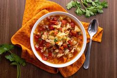 a white bowl filled with soup on top of a wooden table next to a spoon