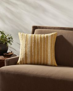 a brown chair with a yellow striped pillow on it