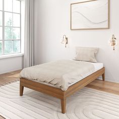 a bed sitting on top of a wooden floor next to a white rug and window