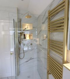 a bathroom with marble walls and flooring, gold trimming on the shower door