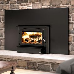 a wood burning stove sitting on top of a stone fireplace