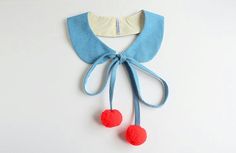 a blue and white bib with red pom - poms hanging from it