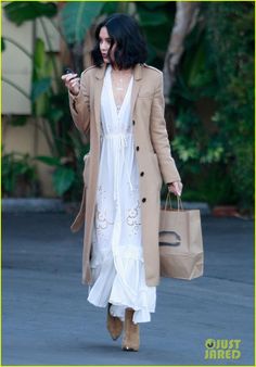 a woman is walking down the street while looking at her cell phone and holding shopping bags