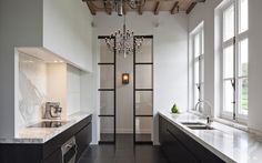 a modern kitchen with marble counter tops and dark wood cabinets, chandelier hanging from the ceiling