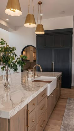 a large kitchen with marble counter tops and gold pendant lights hanging from the ceiling over the sink