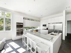 a large kitchen with white cabinets and counter tops, along with an island in the middle