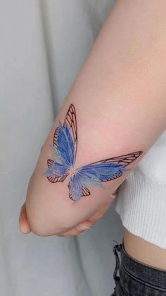 a woman's arm with a blue butterfly tattoo on the left side of her arm