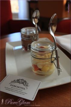 there is a jar with some food in it on the table next to two spoons