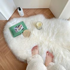 a person is laying on the floor with their feet propped up next to a book and candle