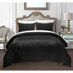 a bed with black comforter and pillows in a room