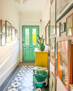 a green door is in the hallway with pictures on the wall and a yellow chair