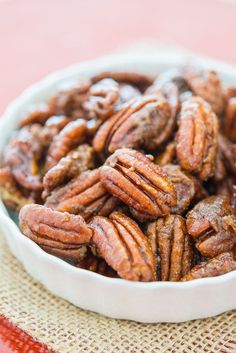 a white bowl filled with pecans sitting on top of a red and white table cloth