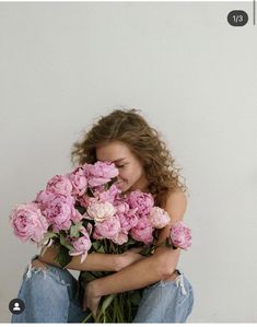 a woman sitting on the ground with flowers in her lap