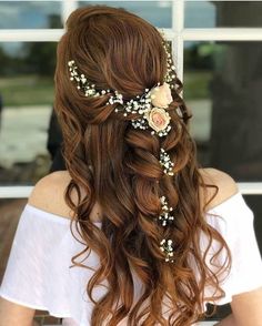 a woman with long brown hair and flowers in her hair is looking out the window