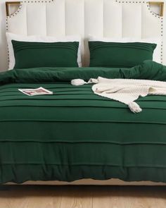 a bed with green sheets and pillows on it