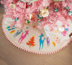 a pink christmas tree skirt with ornaments on it