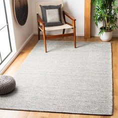 a living room with a chair, rug and potted plant