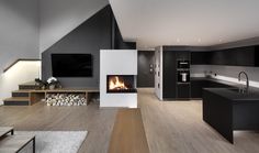 an open concept living room and kitchen with wood flooring, white walls and fireplace