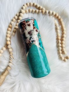 a blue cup sitting on top of a white rug next to a wooden beaded necklace