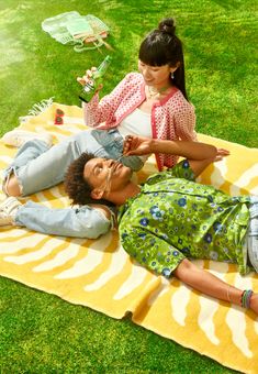 two women laying on a blanket in the grass