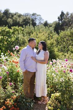 a man and woman standing in a field of flowers