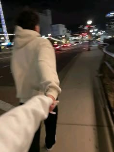 a woman walking down the street at night with her arm wrapped in a white blanket