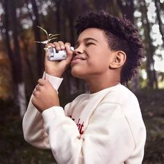 a young boy holding a plant and looking up into the sky with his eyes closed