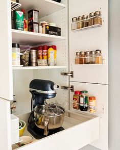 an organized kitchen pantry with food and condiments on the shelves, including a mixer