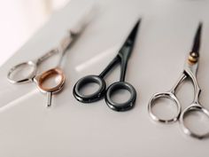 three pairs of scissors sitting on top of a white table next to each other,