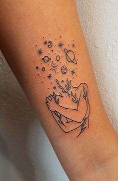 a woman's arm with tattoos on it and stars in the sky above her