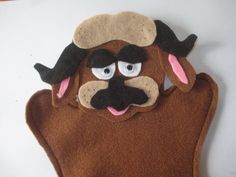 a close up of a stuffed animal on a white surface with a black nose and brown body