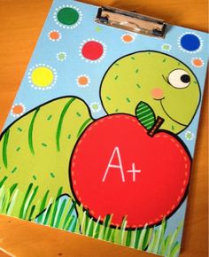 a clipboard with an image of a caterpillar holding a big red apple