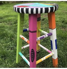 a colorful stool made out of crayons in the grass with measuring tape on it