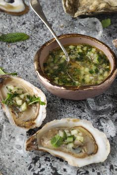 three oysters on ice with a spoon in the bowl and some other food items