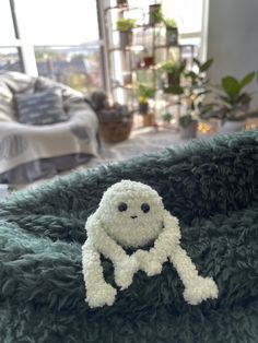 a white stuffed animal sitting on top of a green blanket in front of a bed