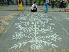 people are standing on the sidewalk with chalk drawings