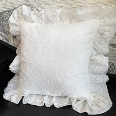 two white pillows with ruffled edges on a black table next to a wooden wall